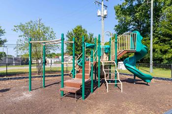 A playground with a green slide and a brown bench.